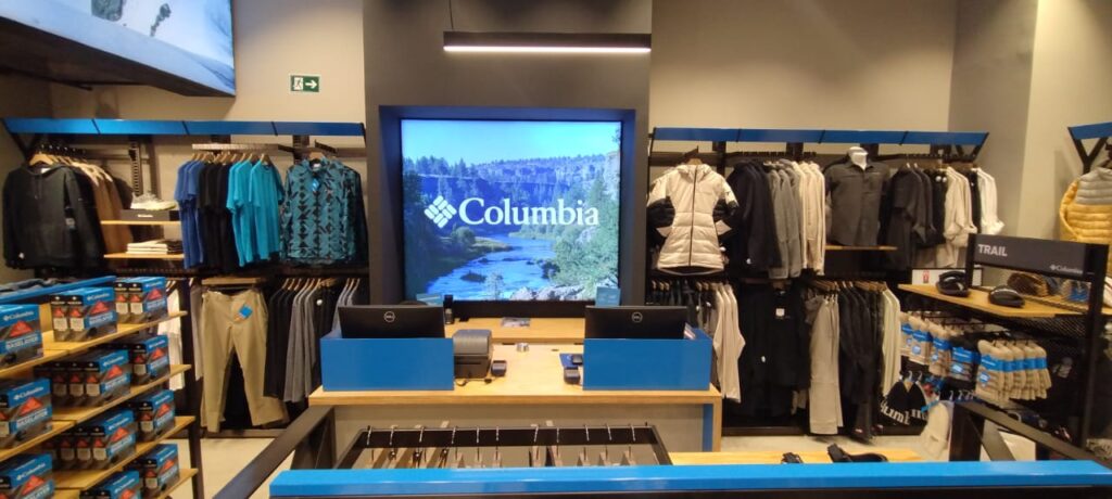 Interior de uma loja Columbia no Brasil, com roupas e acessórios técnicos disponíveis para esportes outdoor.