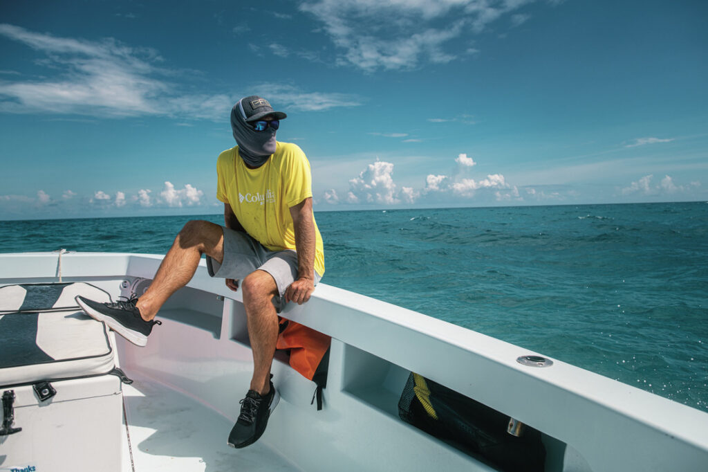 Pescador em barco usando protetor de pescoço Columbia, acessório que protege contra sol, vento e insetos