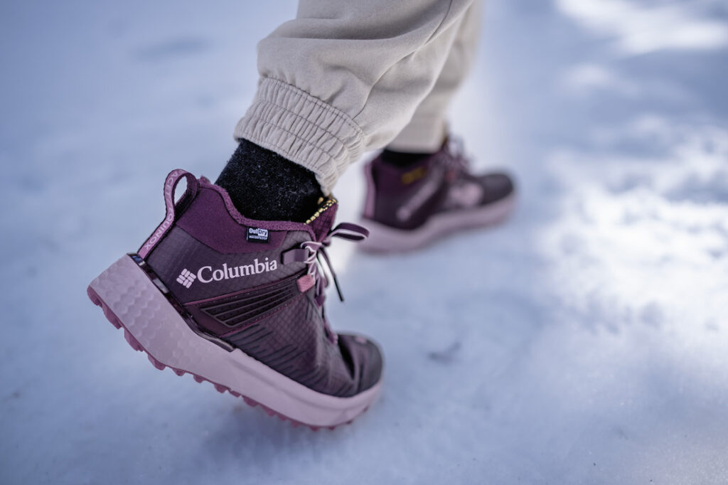 Close em pessoa usando bota Columbia roxa na neve, representando o comparativo para escolher a melhor bota para neve feminina.