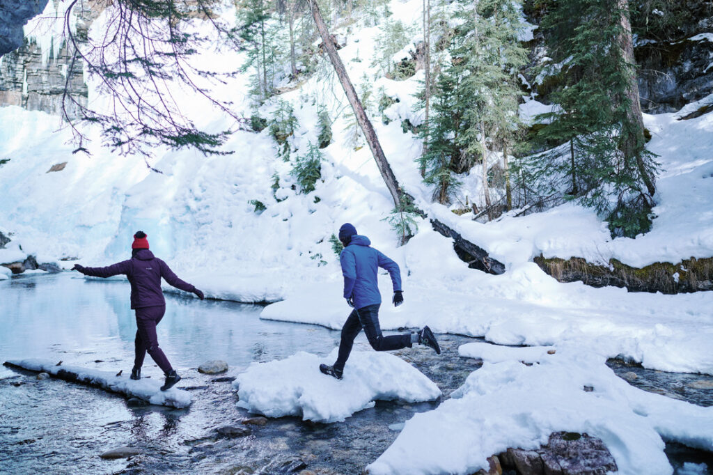 Casal caminhando na neve com botas Columbia, mostrando porque investir na melhor bota para neve feminina é garantia de durabilidade.