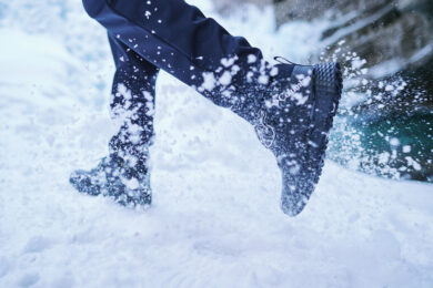 Pessoa correndo na neve com bota Columbia preta, representando a melhor bota para neve feminina com tração e proteção em ambientes gelados.