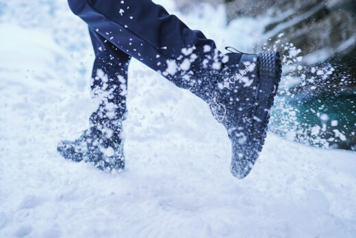 Pessoa correndo na neve com bota Columbia preta, representando a melhor bota para neve feminina com tração e proteção em ambientes gelados.