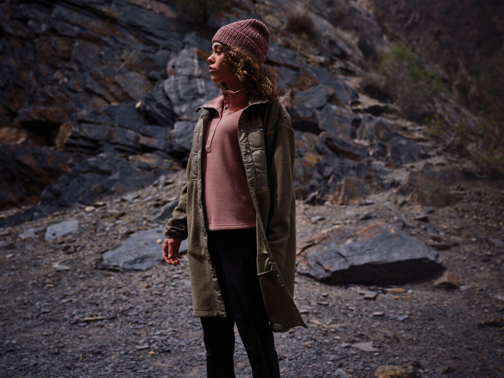 Pessoa usando blusa térmica Columbia em ambiente rochoso, mostrando o conforto e o isolamento da primeira camada para o frio.