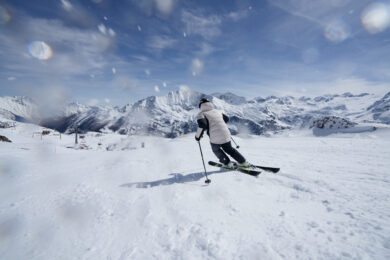Pessoa esquiando em pista nevada com roupa Columbia, mostrando performance e conforto nas montanhas.